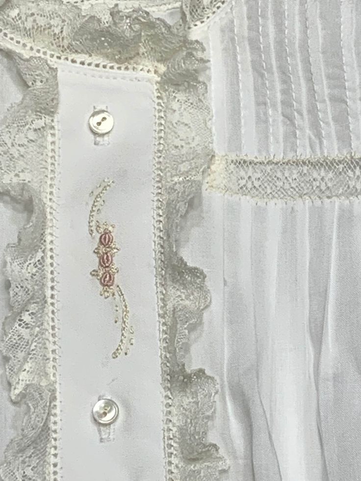 a white shirt with buttons and lace on it