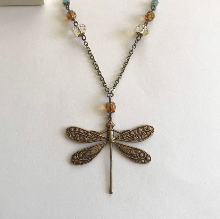 "Here is a fabulous art nouveau style dragonfly necklace, which features an amazing embossed brass dragonfly with very nice detailing throughout. There are a variety of faceted Czech glass beads strung onto the chain in the colors of aqua blue, amber and champagne. The chain is a very good quality, soldered brass chain, the clasp is solid brass. Necklace comes shipped in a sweet Botanical Bird gift box. Note: this dragonfly pendant is 100% brass, not amalgam metal. Pendant measures: 1.75\" acros Oak Leaf Necklace, Lily Necklace, Art Nouveau Necklaces, Vintage Dragonfly, Victorian Necklace, Dragonfly Jewelry, Blue Amber, Red Pendants, Dragonfly Necklace