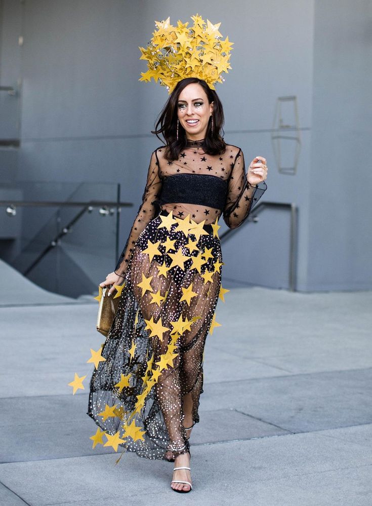 a woman in a black and yellow outfit with stars on her head is walking down the street