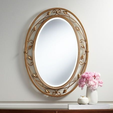 a mirror sitting on top of a dresser next to a vase with flowers in it