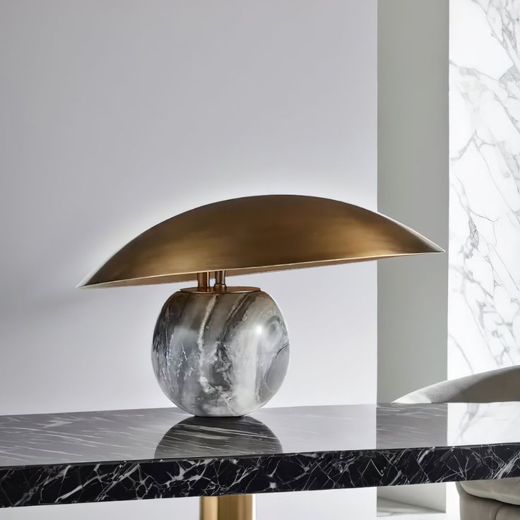 a table lamp sitting on top of a black marble topped table next to a white wall