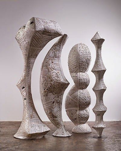 three white sculptures sitting next to each other on a cement floor in front of a wall