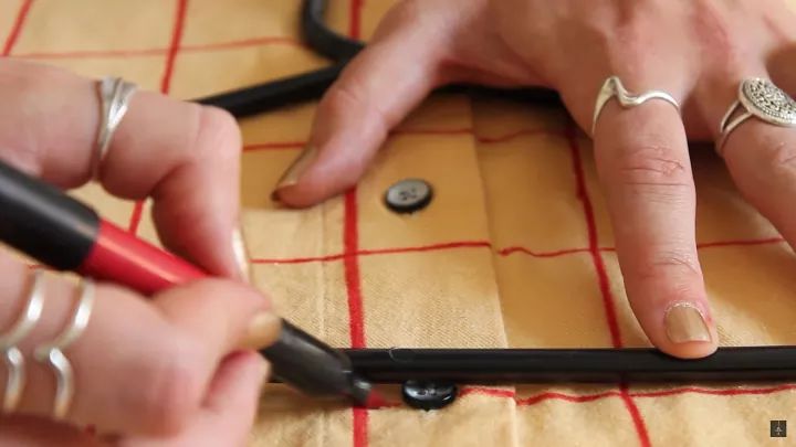 two hands with rings on their fingers are working on some sewing thread and buttons, while another hand is holding a pair of scissors