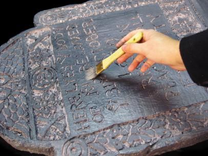 a person using a brush to paint on a decorative object