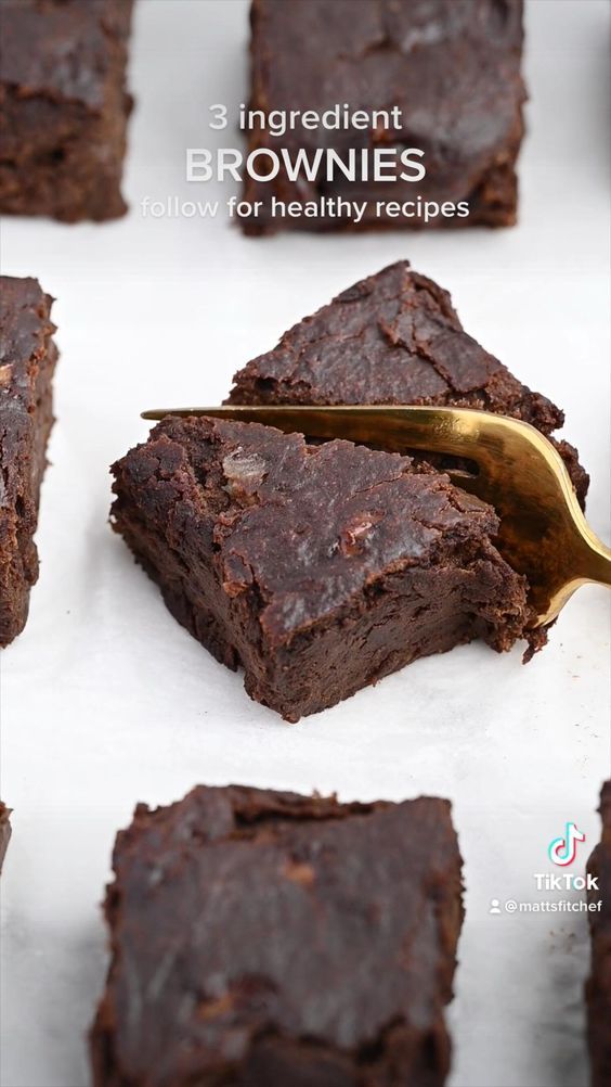 brownies are being cut into squares with a gold spoon in the middle and on top