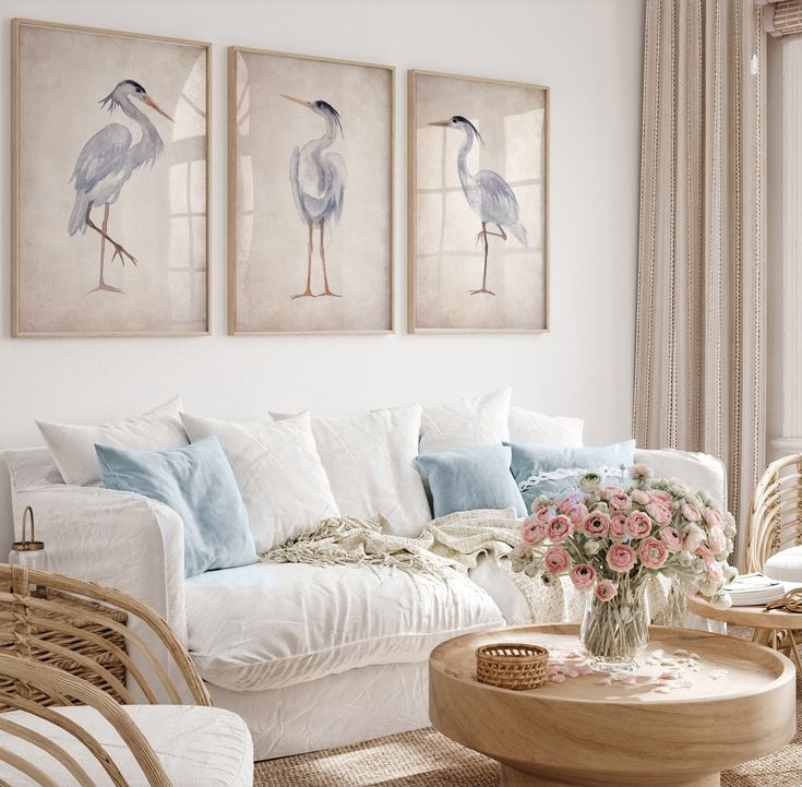 a living room with wicker furniture and paintings on the wall above it's windows