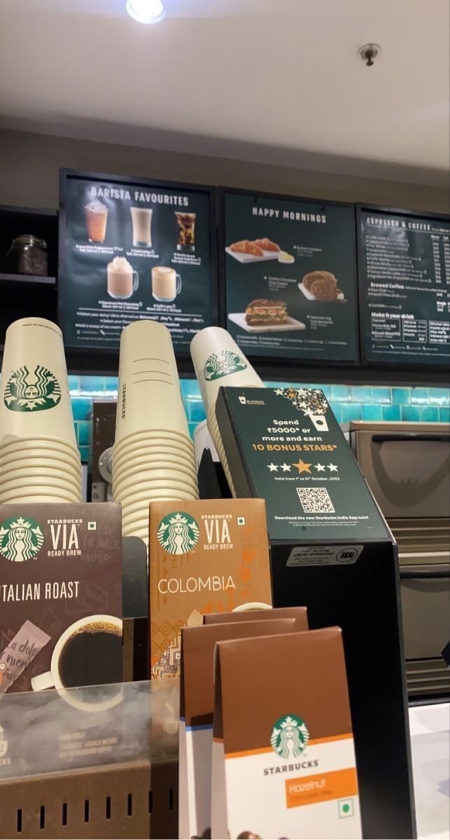 starbucks coffee cups are on display at the counter in front of menus and other items