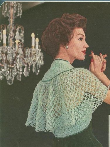 the woman is wearing a crocheted shawl and holding her hands up to her chest