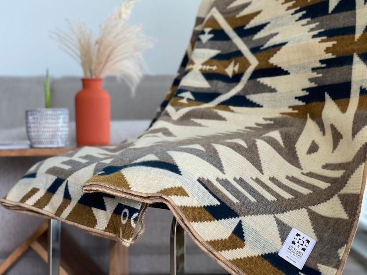 a brown and white blanket sitting on top of a wooden chair next to a table