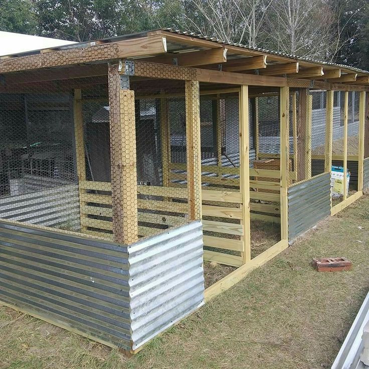 an outdoor chicken coop in the middle of a yard with metal and wood sidings