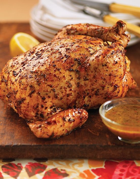 a whole chicken on a cutting board next to some dipping sauce