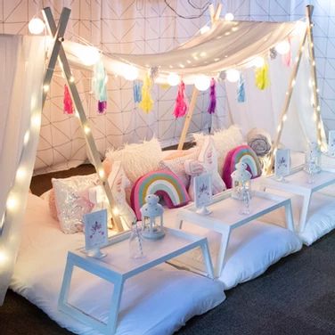 a canopy bed with pillows and lights on the top is set up for a party