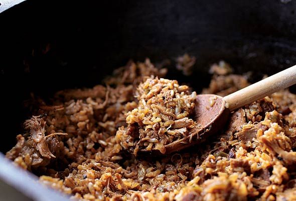 a pan filled with food and a wooden spoon on top of the pot full of it