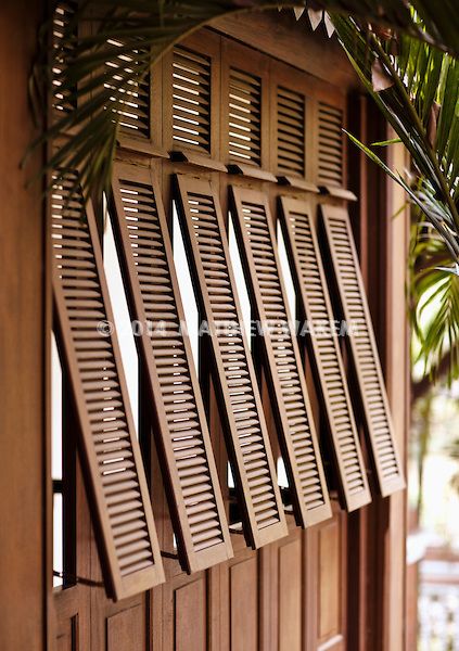 wooden shutters on the side of a building with palm trees in the foreground