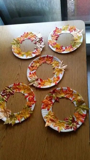 four plates with leaves on them sitting on top of a table next to a window