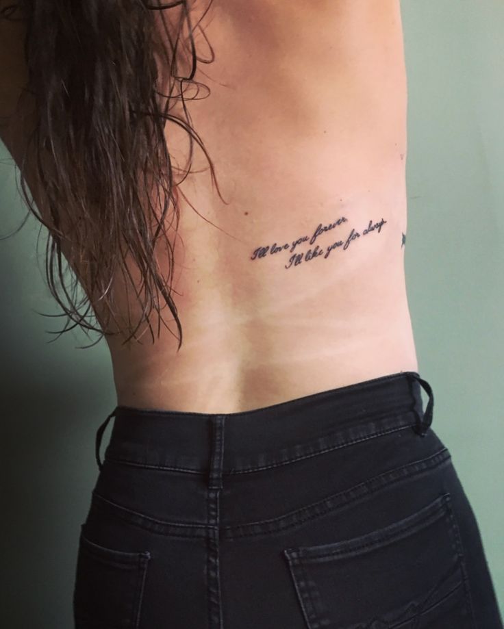 the back of a woman's stomach with words written on her left ribcage