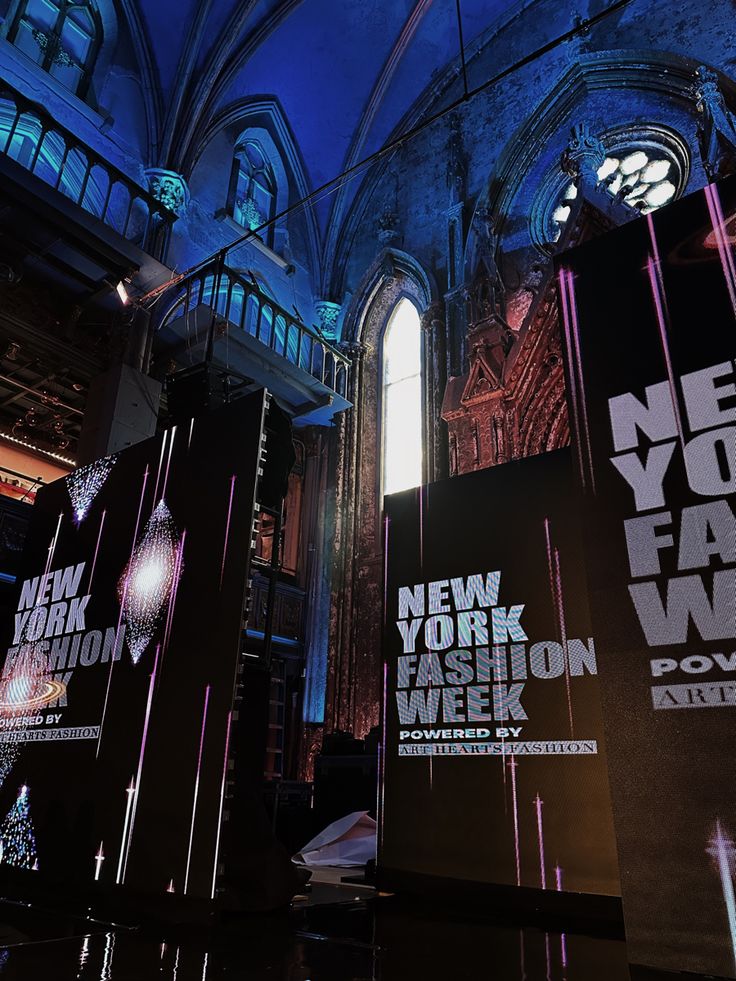 the new york fashion week poster is lit up in front of an ornate building at night