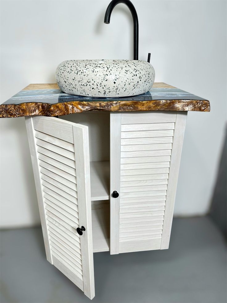 a white cabinet with a sink and black faucet on it's side