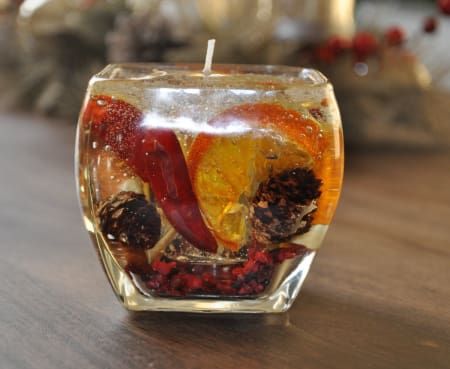 a glass candle holder filled with fruit and veggies on top of a wooden table