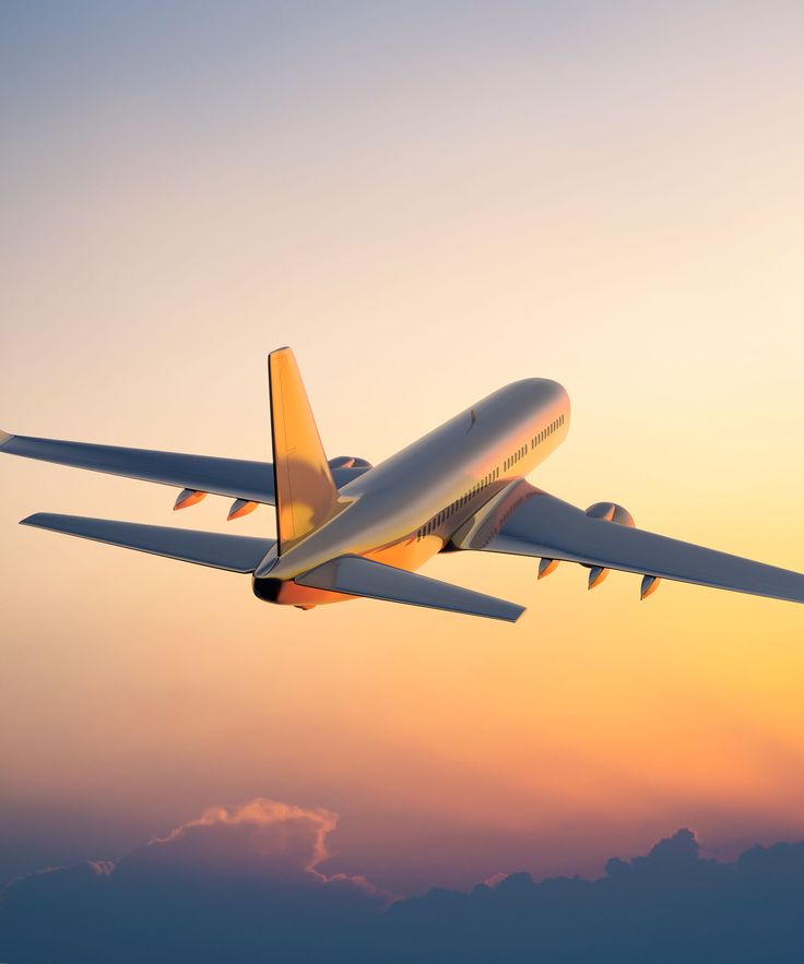 an airplane flying in the sky at sunset