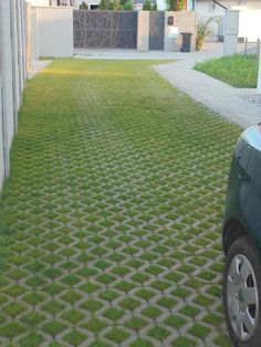 a car parked in front of a house with grass growing on the driveway and sidewalk