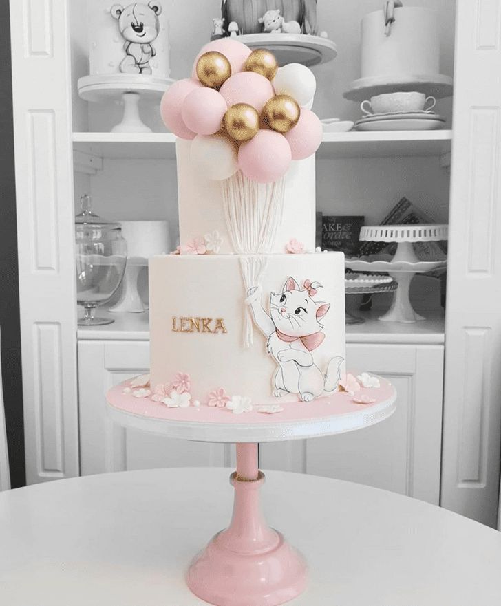 a pink and white cake with gold balloons on top