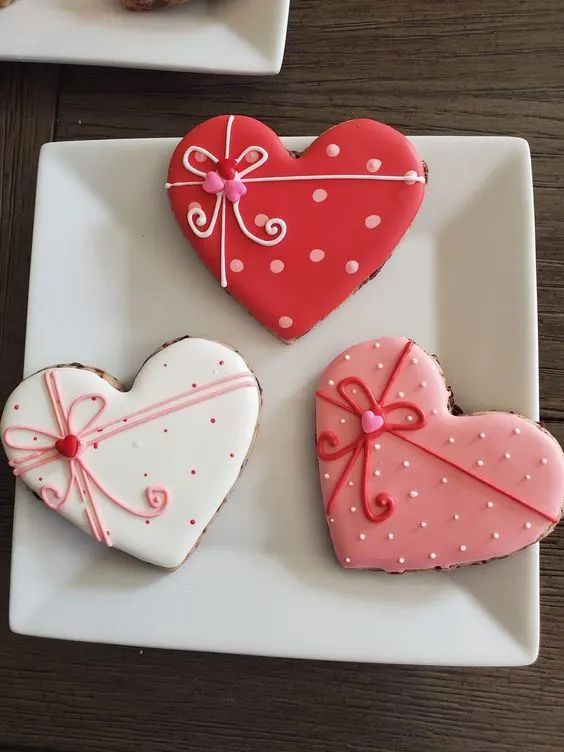 three decorated heart shaped cookies on a plate