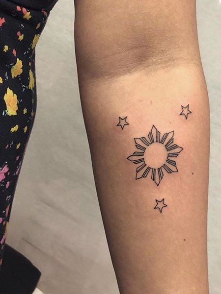 a woman's arm with a small sun and stars tattoo on the left forearm