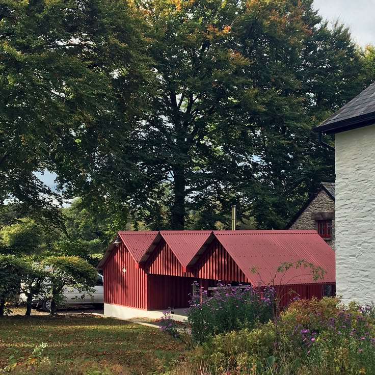 a white building with red roof next to trees