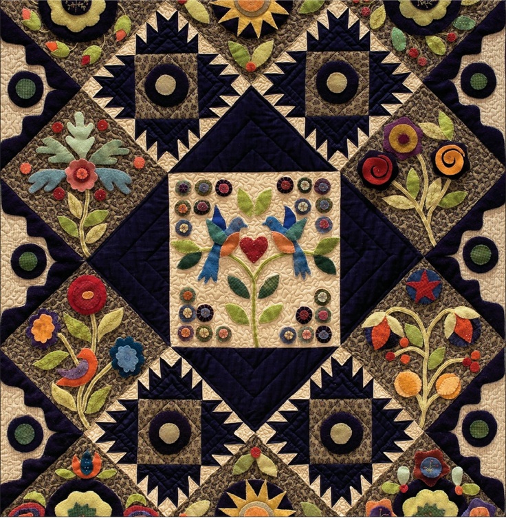 a quilted wall hanging with flowers and leaves on it's sides, in the shape of a square