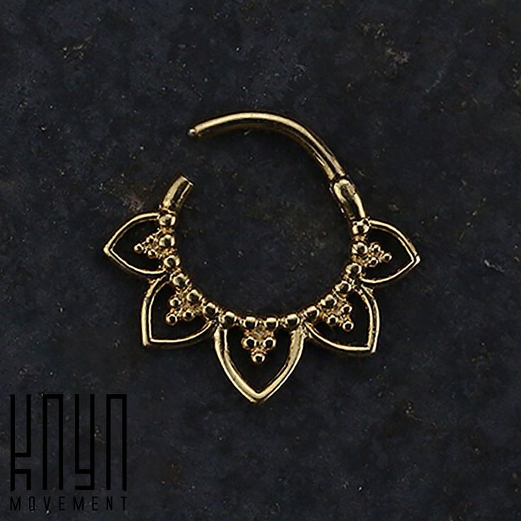 a gold nose ring with an intricate design on the end and small beads hanging from it