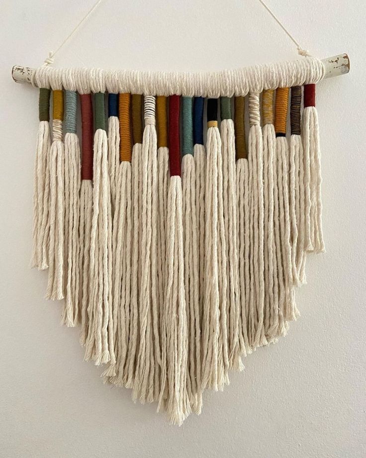 a white wall hanging with multicolored tassels on it's sides