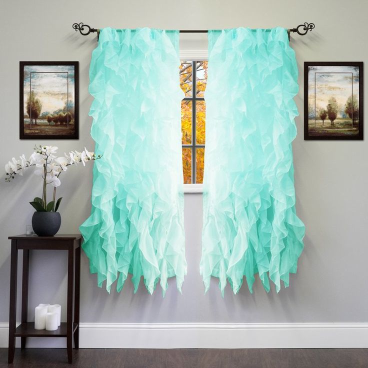 a room with two pictures on the wall and one has a blue feathered curtain