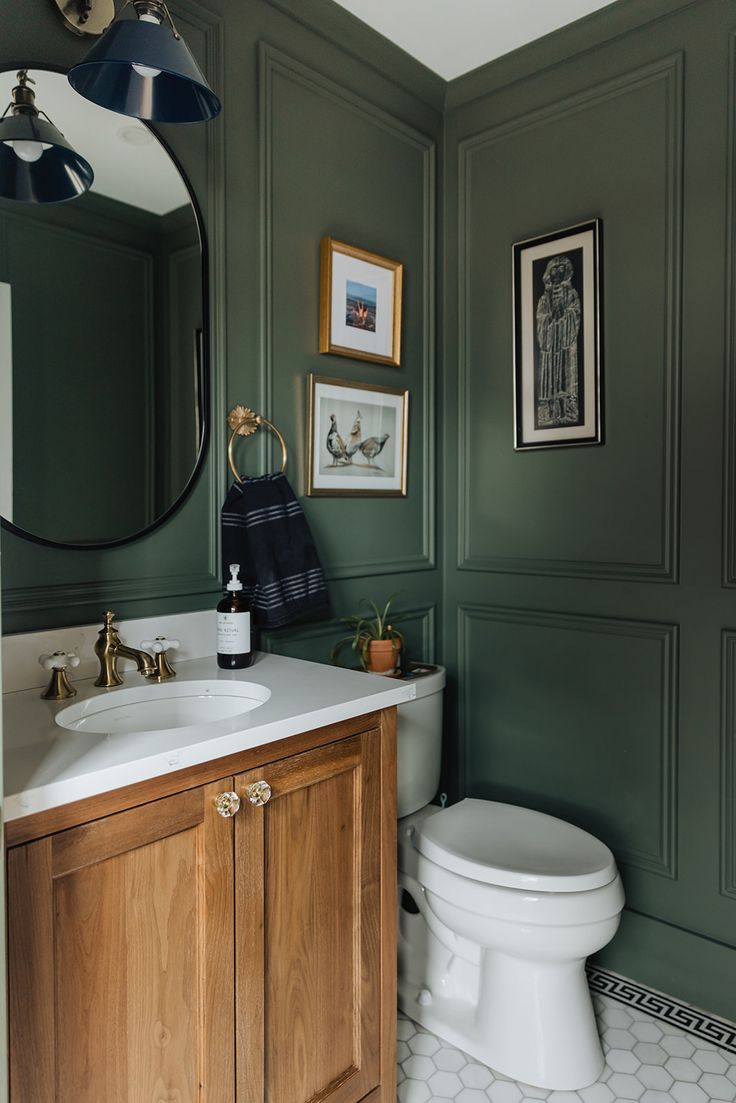 a white toilet sitting next to a wooden cabinet in a bathroom under a round mirror