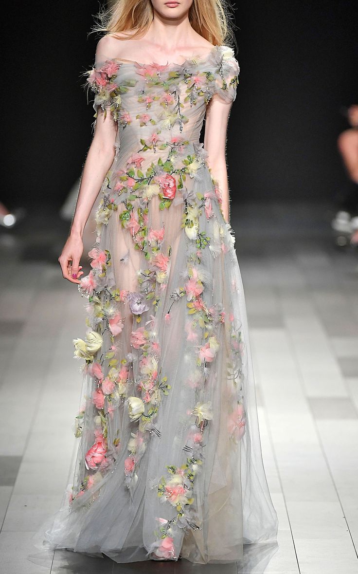 a model walks down the runway in a floral dress with sheer tulle and flowers on it