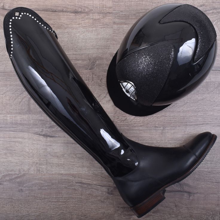 a pair of black shoes and a helmet on top of a wooden floor next to each other