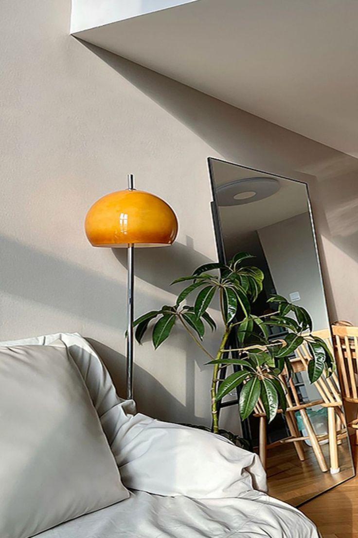 a living room with a couch, mirror and potted plant