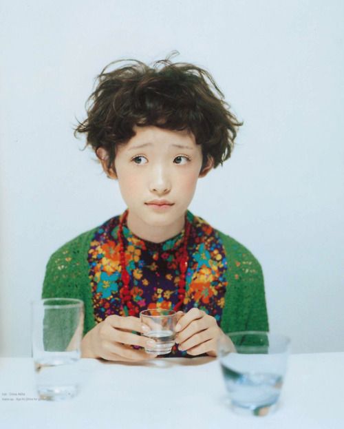 a young boy sitting at a table with two glasses