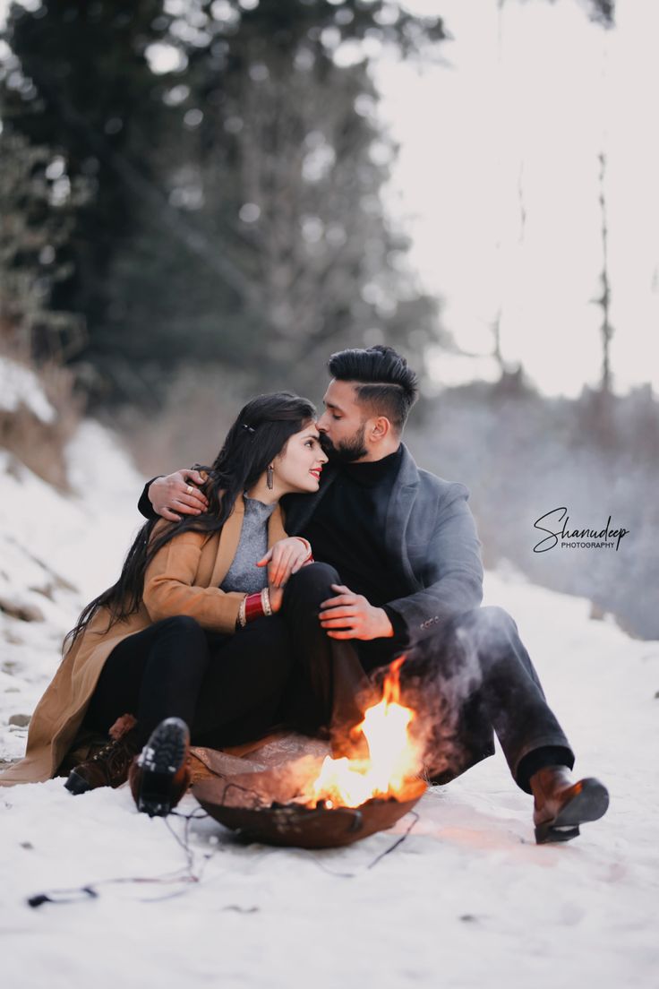 a man and woman sitting next to each other on top of a snow covered ground