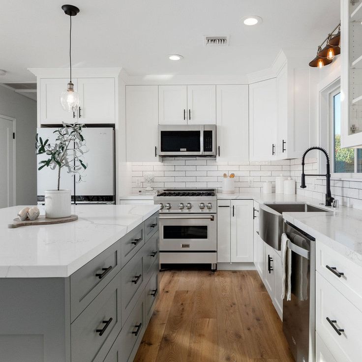 a large kitchen with white cabinets and stainless steel stove top oven, dishwasher, microwave and sink