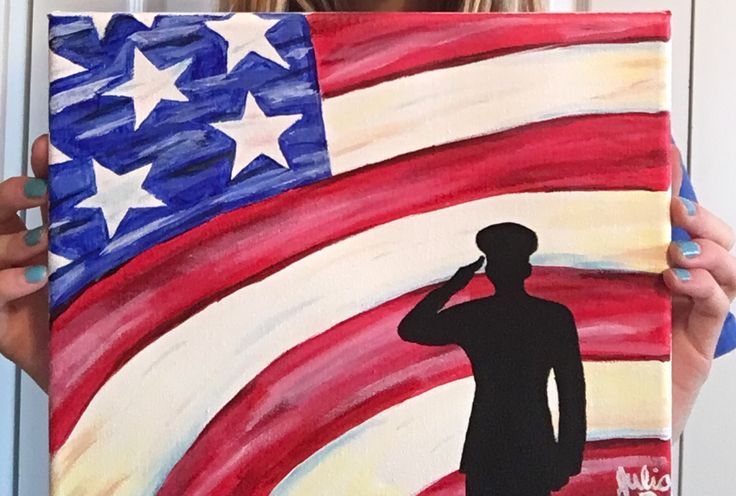 a woman holding up a painting of a soldier in front of an american flag background