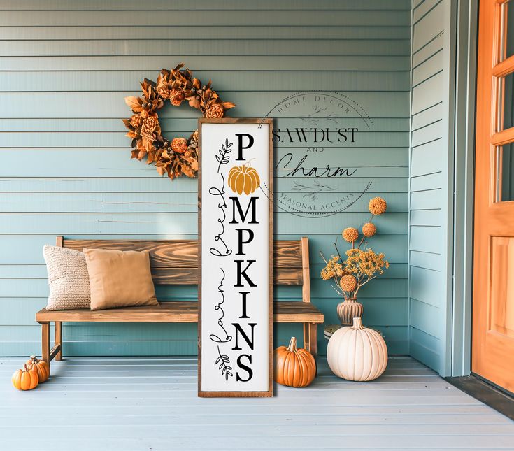 a wooden sign sitting on the side of a house next to a bench and pumpkins