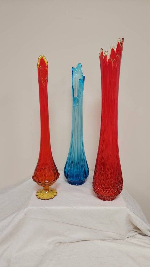 three red and blue vases sitting on top of a white cloth covered tablecloth