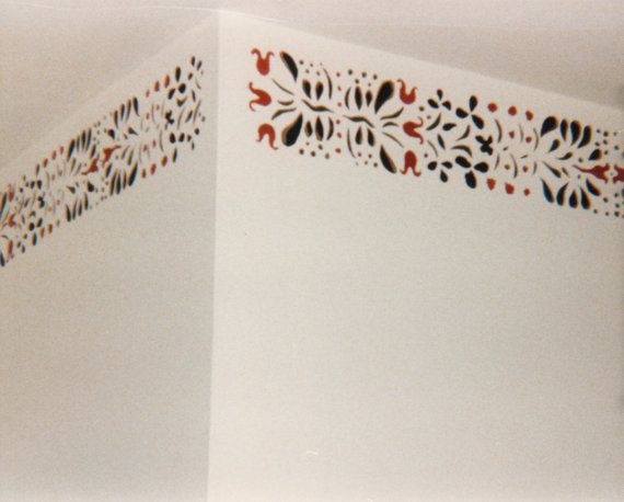 the corner of a white wall with red and black designs on it