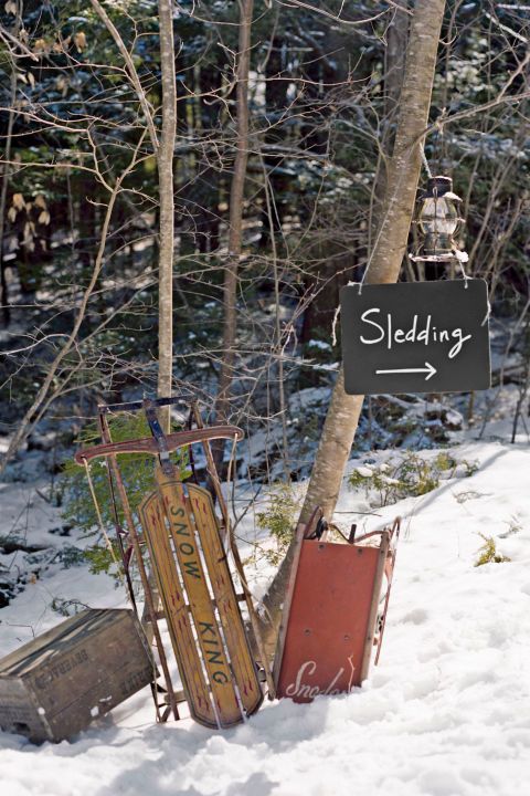 a pile of skis sitting in the snow next to a sign that says sledding