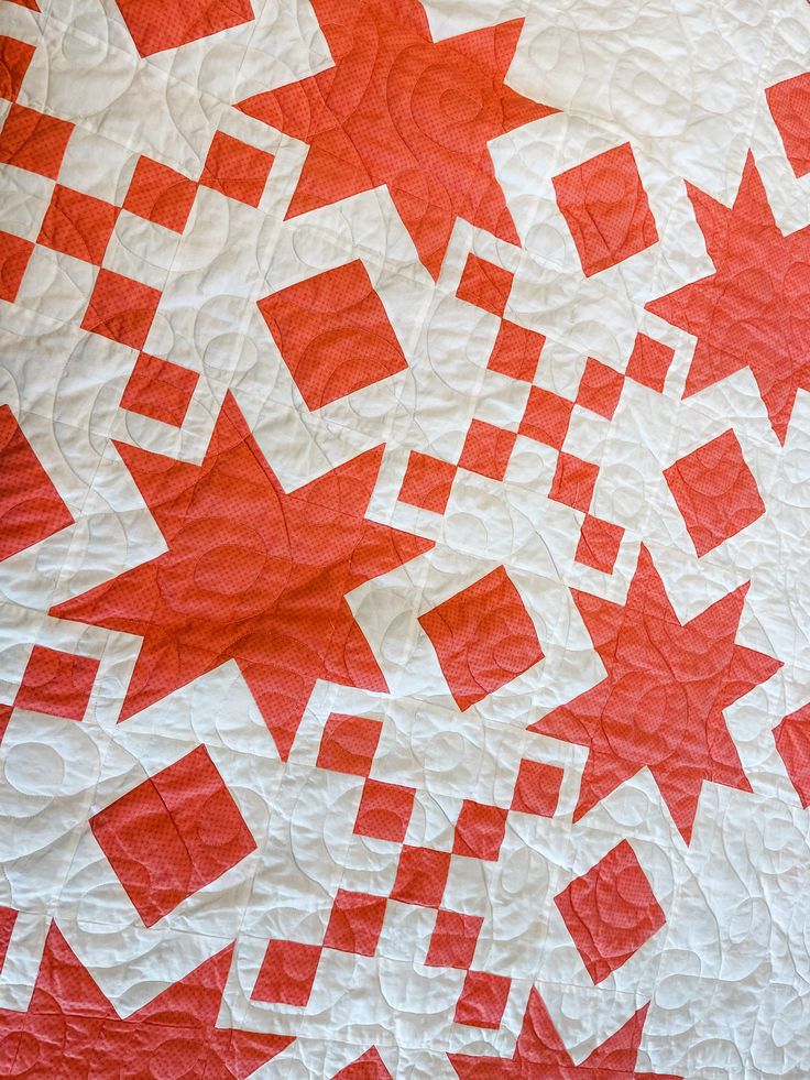 an orange and white quilt with red stars on it