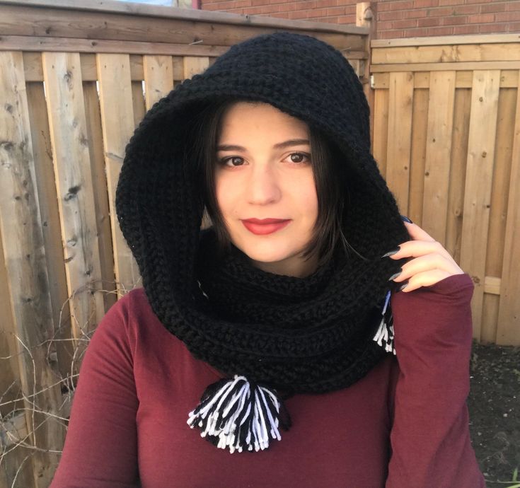 a woman wearing a black scarf with tassels and a hood on her head