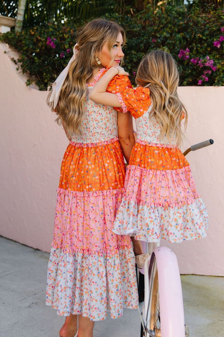 The patchwork dress of your DREAMS now available in bright and bold colors! The Emily Dress features the most fashion forward design, consisting of orange, pink, and stunning floral fabric. She also has an Ivy Favorite smocked bodice, tiered skirt, and dainty puff sleeves. This dress screams, "Ready for Summer" and will be your go-to dress for all your upcoming adventures! Available in size XXS, XS, S, M, L, XL, XXL, 1X, 2X, 3X, 4X, & 5X + kids! Mommy And Me Dress Pattern, Playful Multicolor Tiered Dress, Multicolor Maxi Dress With Smocked Back For Garden Party, Pink Smocked Bodice Maxi Dress For Garden Party, Multicolor Smocked Bodice Dress For Garden Party, Fitted Orange Dress With Smocked Bodice, Multicolor Smocked Bodice Dress For Spring, Spring Multicolor Dress With Smocked Bodice, Multicolor Floral Patchwork Maxi Dress For Spring