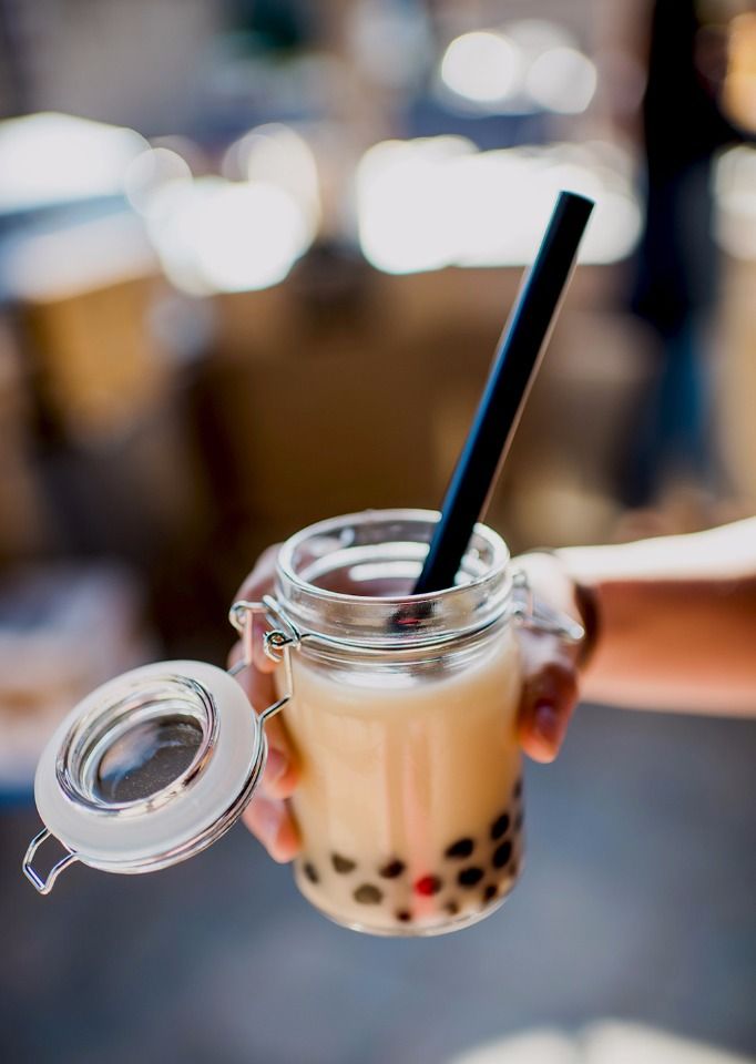 a person holding a drink with a straw in it's glass cup and lid