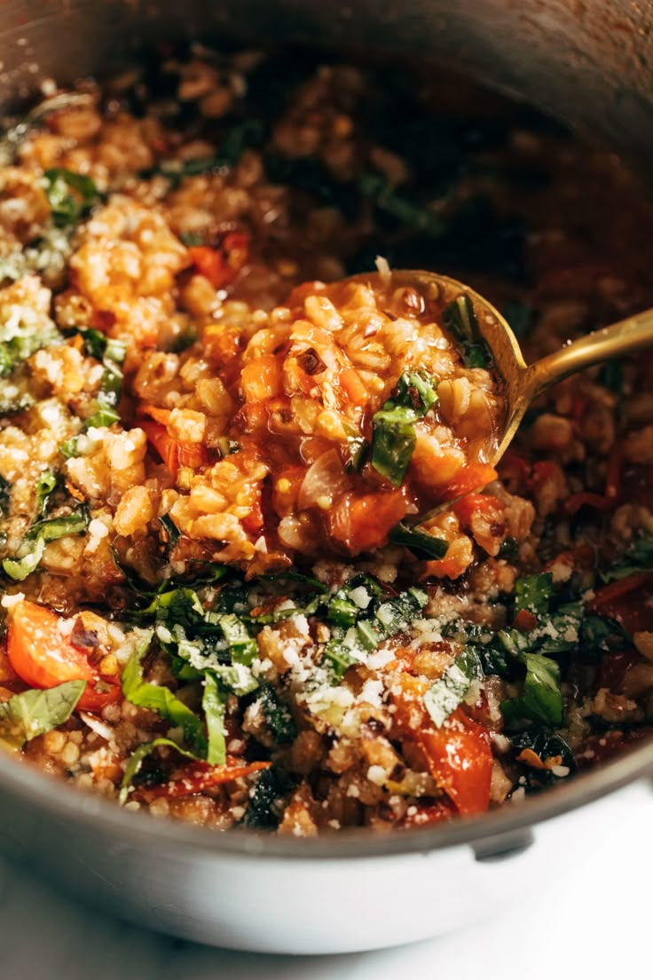 a pot filled with rice and vegetables on top of a stove next to a wooden spoon